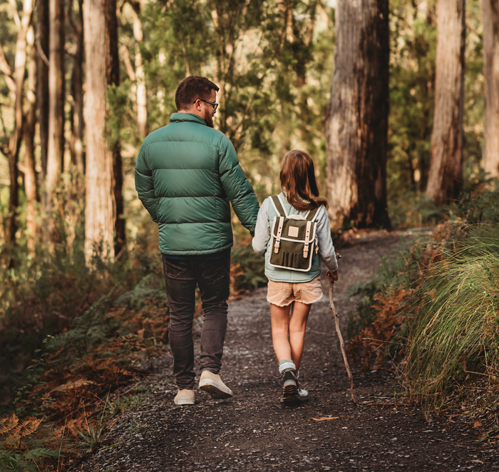 Man and child walking hand in hand on a forest path