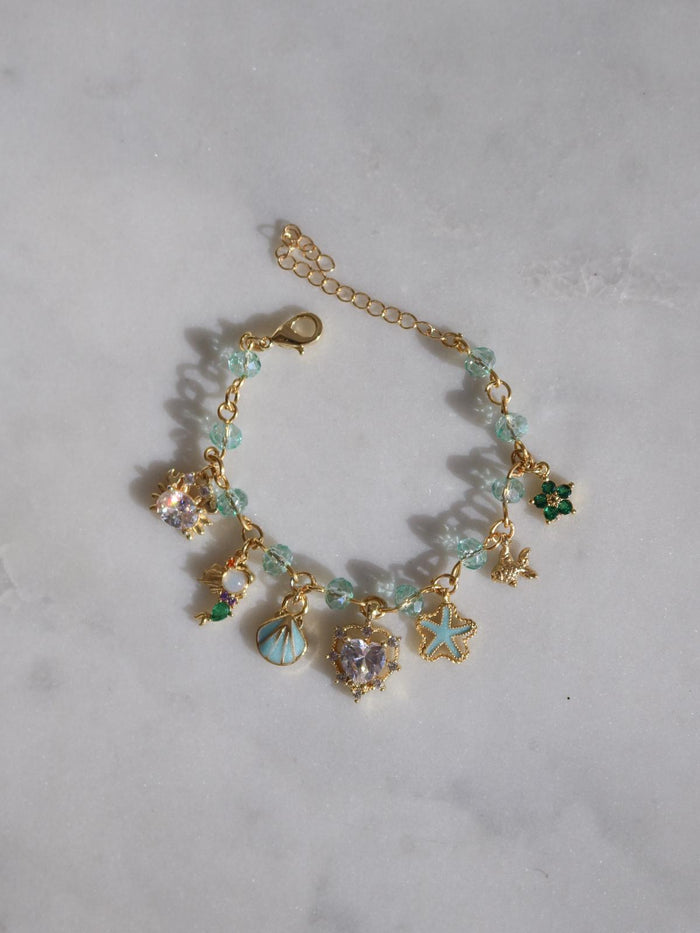 Gold bracelet with charms on a light gray background