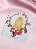 Bracelet with charms on a card featuring a princess illustration, on a pink satin background.