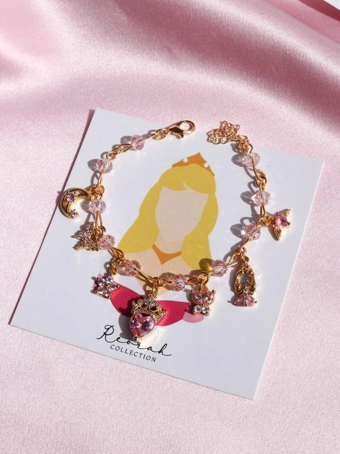 Bracelet with charms on a card featuring a princess illustration, on a pink satin background.
