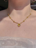 A person wearing a gold-colored Belle's Rose Heart Necklace with a rose-shaped pendant, displayed against a neutral background.