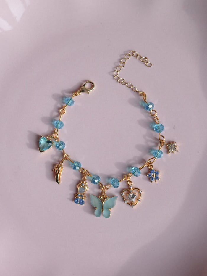 Cinderella Charm Bracelet with blue beads and butterfly charms on a light pink background