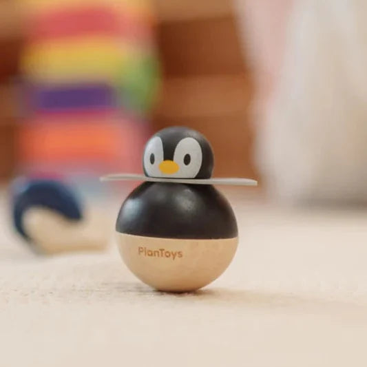 Wooden penguin toy with 'PlanToys' branding on a wooden surface.
