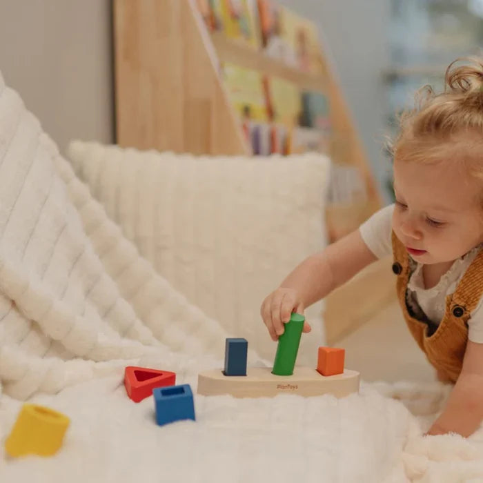 Child playing with colorful wooden blocks on a soft surface