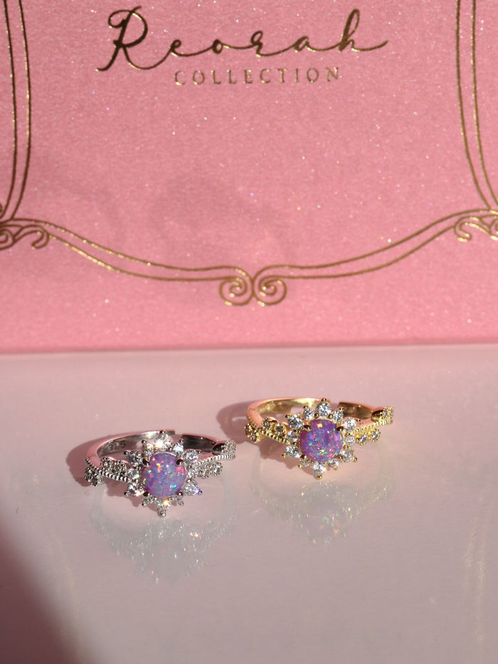 Rapunzel Dream Sun Opal Ring, 925 Sterling Silver with opal centers, one with a silver band and the other with a gold band, displayed on a pink surface with the Reorah Collection branding in the background.